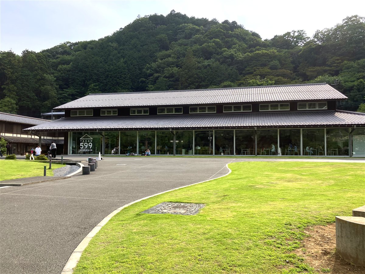 山を背にしたTAKAO 599 MUSEUMの外観と芝生の広場