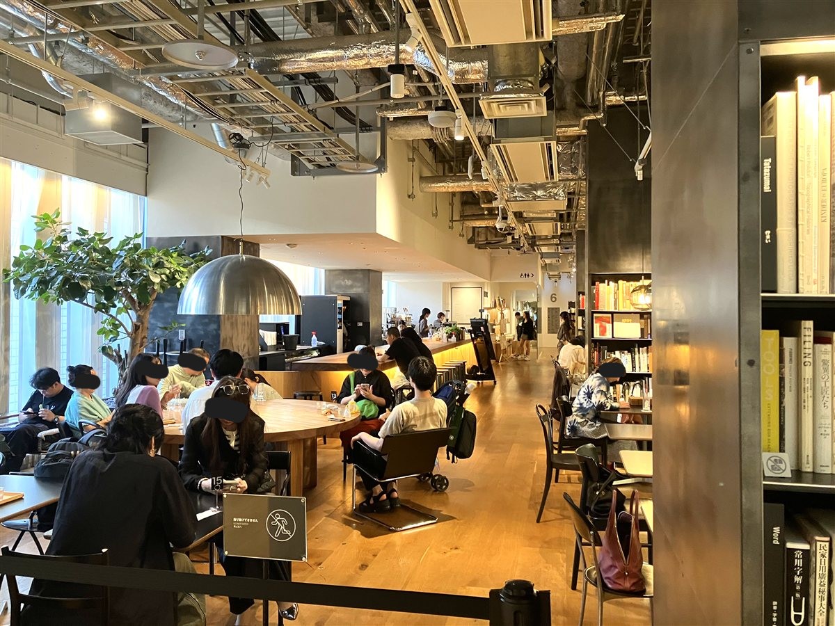Coffee & Salonの店内。大きな丸テーブルと本棚、シンボルツリー