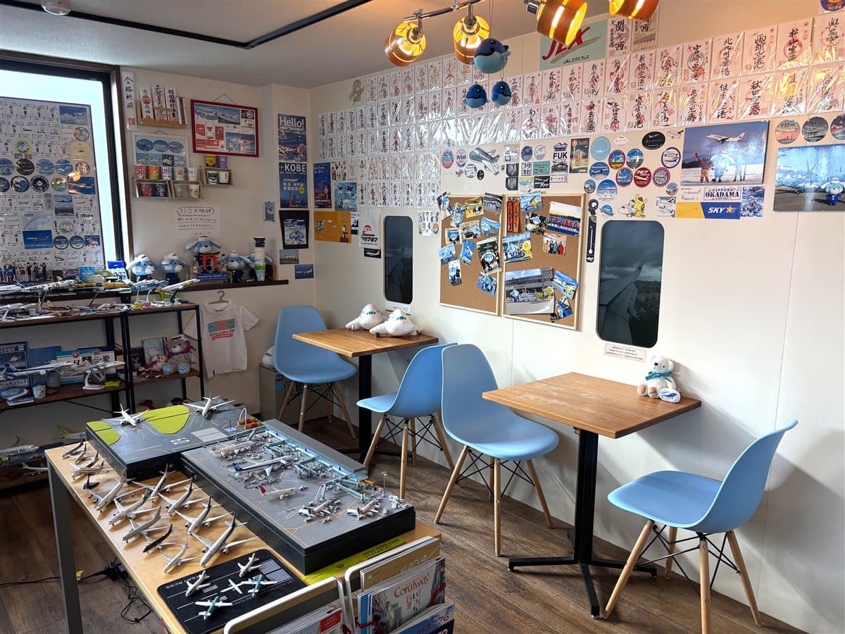 ヒコーキカフェ ハミングバードの店内。壁一面の空港カードと飛行機の窓型モニター