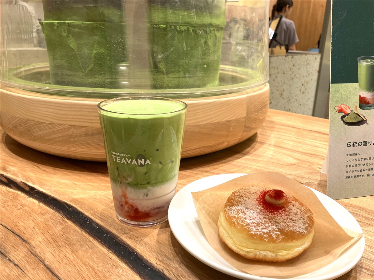 石臼の前に置かれた抹茶とストロベリーの層が美しいドリンクとボンボローニ
