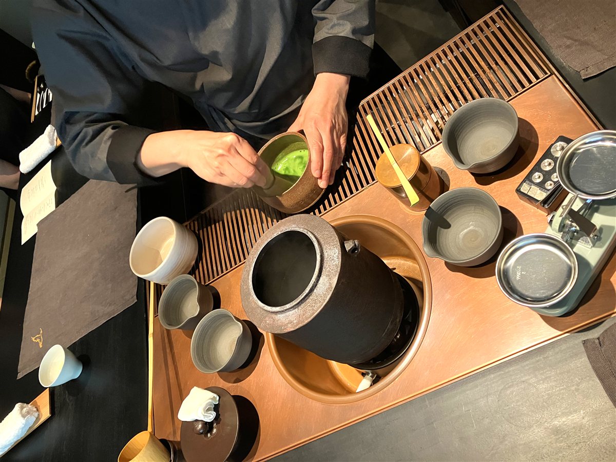 茶道具が並ぶカウンターで抹茶を点てる様子