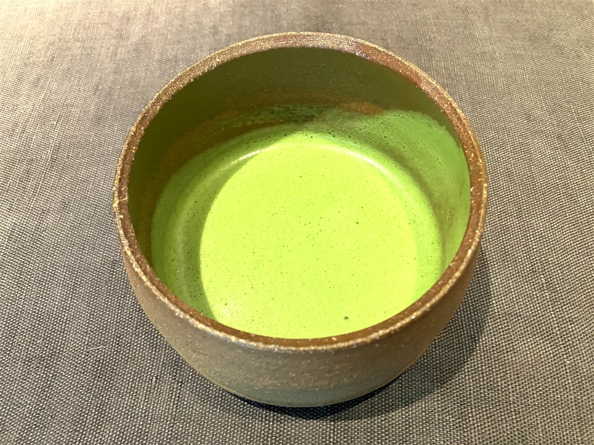 陶器の茶碗に点てられた鮮やかな緑色の抹茶