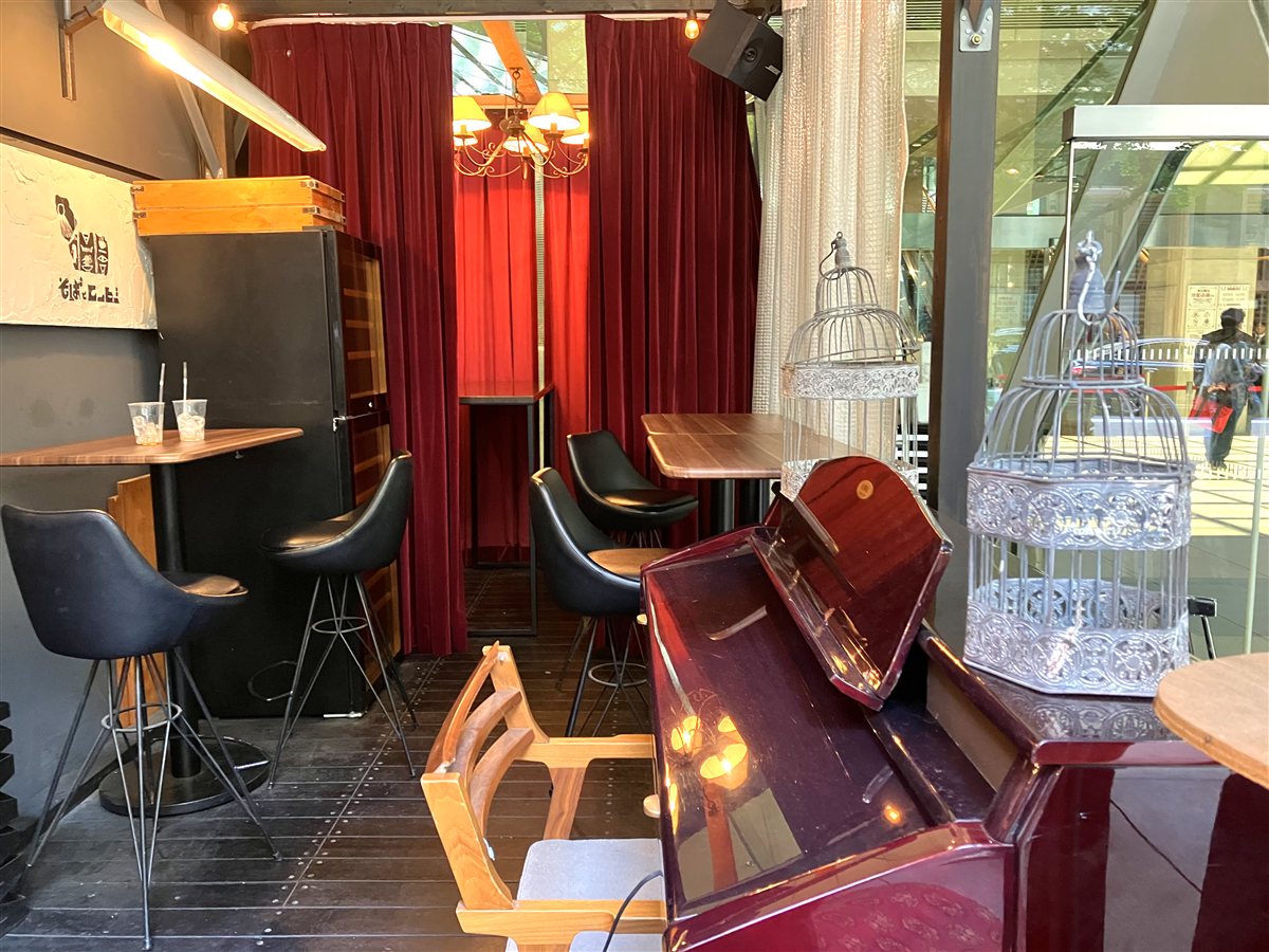 赤いカーテンと鳥かご、ピアノが置かれた店内の一角