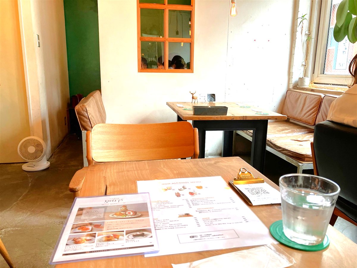 cafe WALLの店内。白い壁と深い緑の壁、木枠の内窓とレザーのソファ席