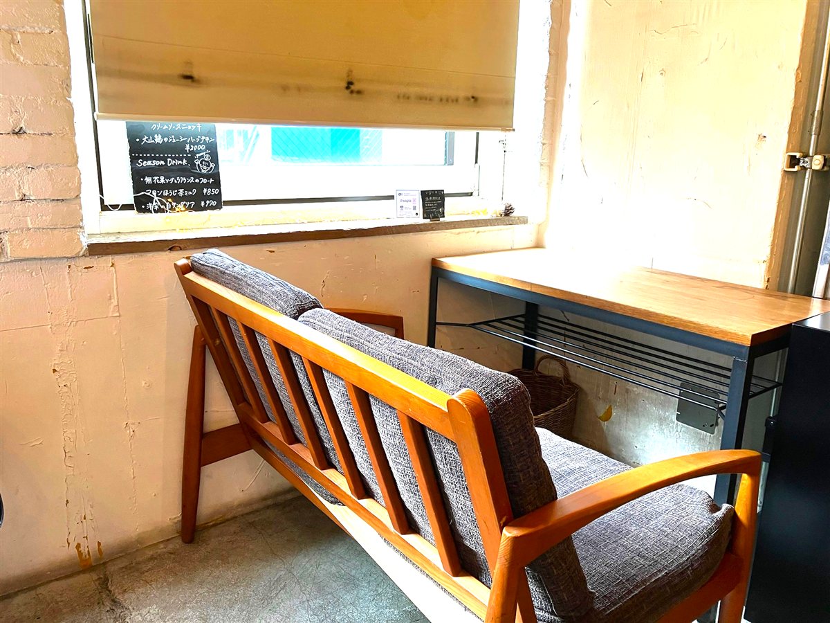 cafe WALLの窓際のソファ席と、季節限定ドリンクが書かれた黒板
