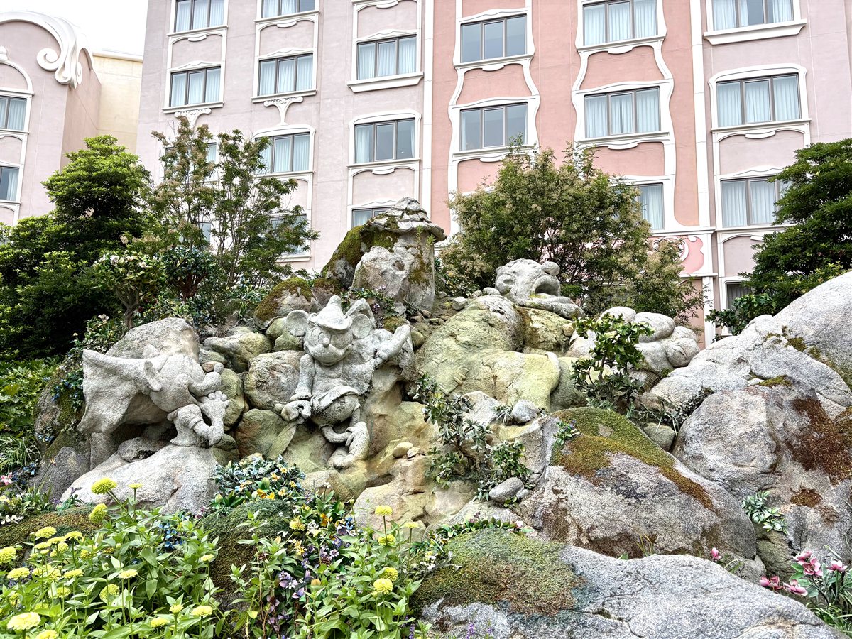 ピンクの建物の前にあるとんがり帽子のミッキーの岩の彫刻