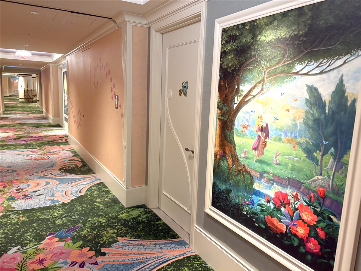 オーロラ姫の絵画と花柄カーペットが続く客室階の廊下