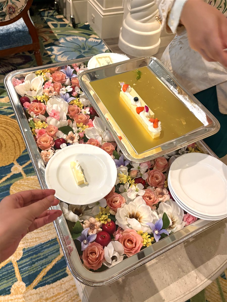 花で敷き詰められたワゴンに乗せられたお祝いのケーキ